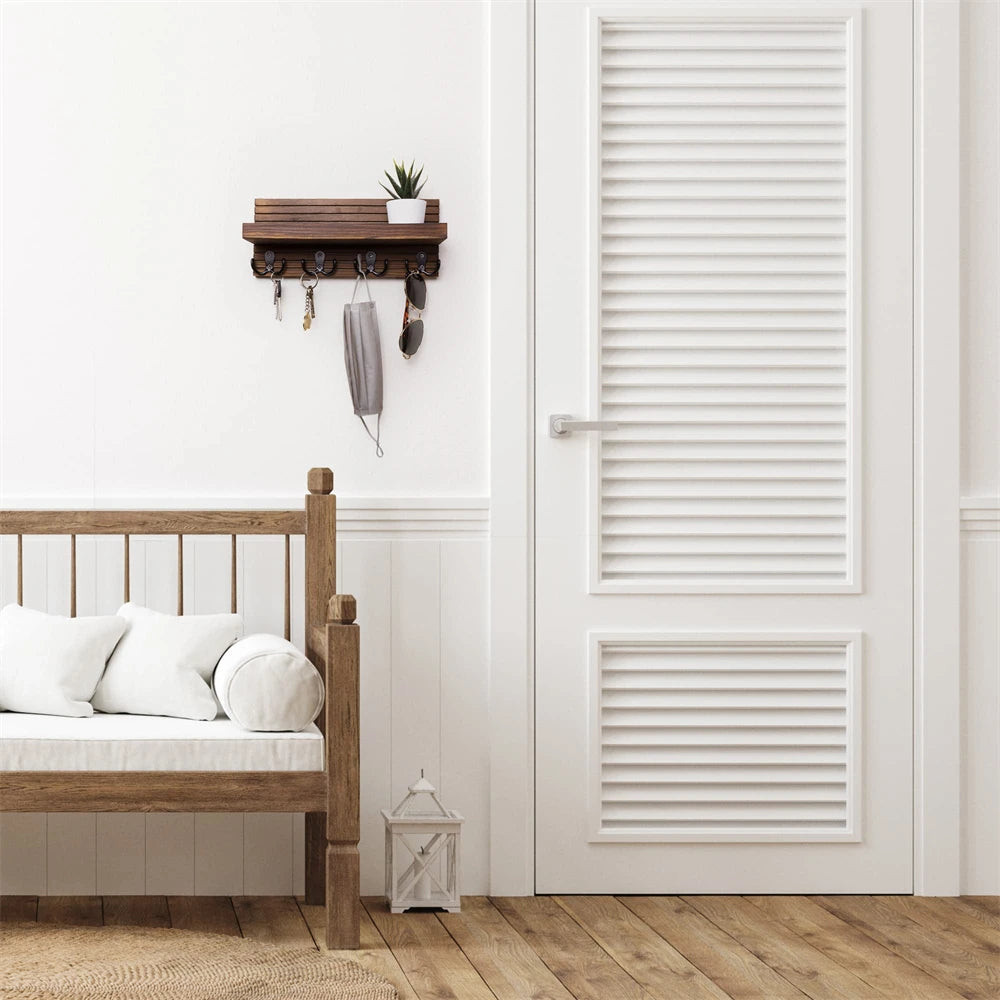 A rustic wooden key holder organizer mounted on a white wall next to a wooden bed frame.