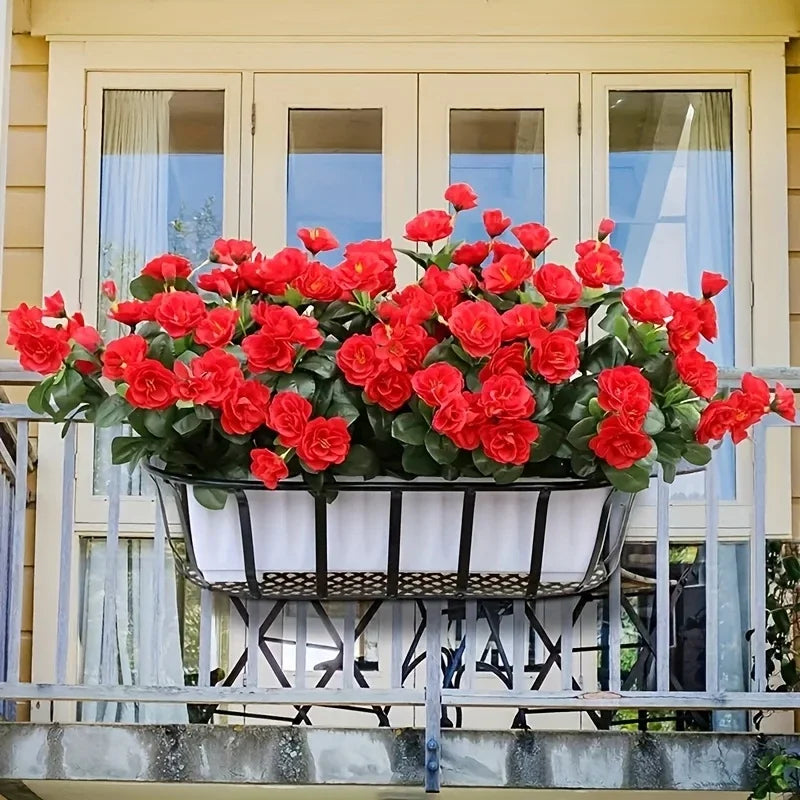 A planter filled with bright red artificial roses is displayed on a balcony railing.