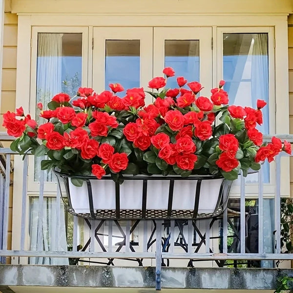 A planter filled with bright red artificial roses is displayed on a balcony railing.