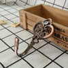 A pair of vintage crown curtain hooks with silver and bronze accents resting on a wooden box.