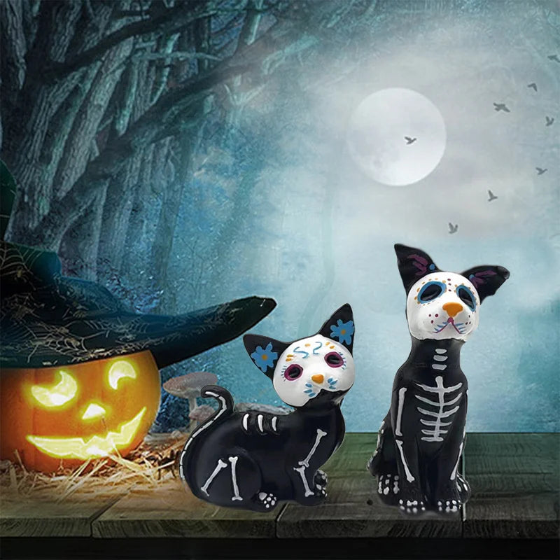 A resin figurine set featuring a black cat and a white dog, styled like Day of the Dead skulls against a blue background.