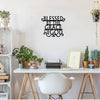 Black metal wall art sign with the text Blessed by The Grace of God displayed on a white desk.