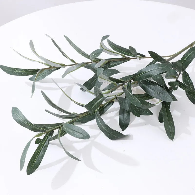 An artificial olive branch with leaves and small fruits in silk green for home and event decor.