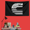 A black flag featuring the Cummins engine logo in white, with stars and horizontal stripes, displayed on a red wall.