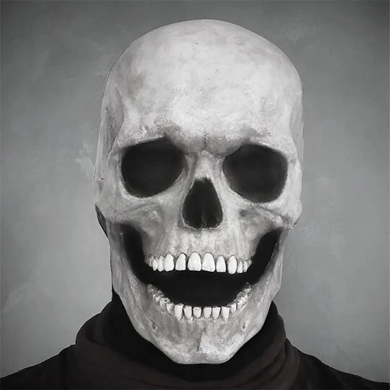 A grayscale photo of a realistic human skull mask with a wide, toothy grin.
