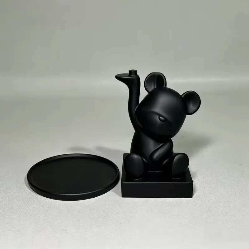 A black bear-shaped jewelry and accessory tray with a small, curved horn resting on a dark square base.