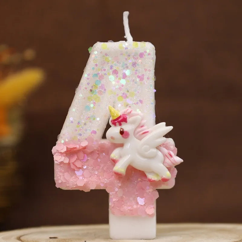 Vela blanca con forma de 4 decorada con purpurina rosa y una pequeña figura de unicornio blanco.