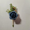 A small bouquet featuring a dusty blue silk rose, green foliage, and gold accents.