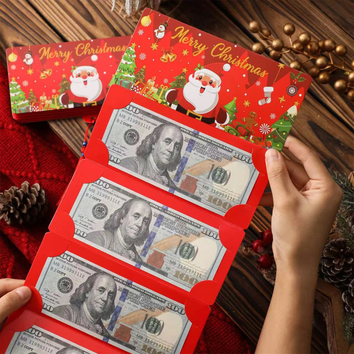 A hand holds a festive red card box with Christmas designs and multiple slots for money.