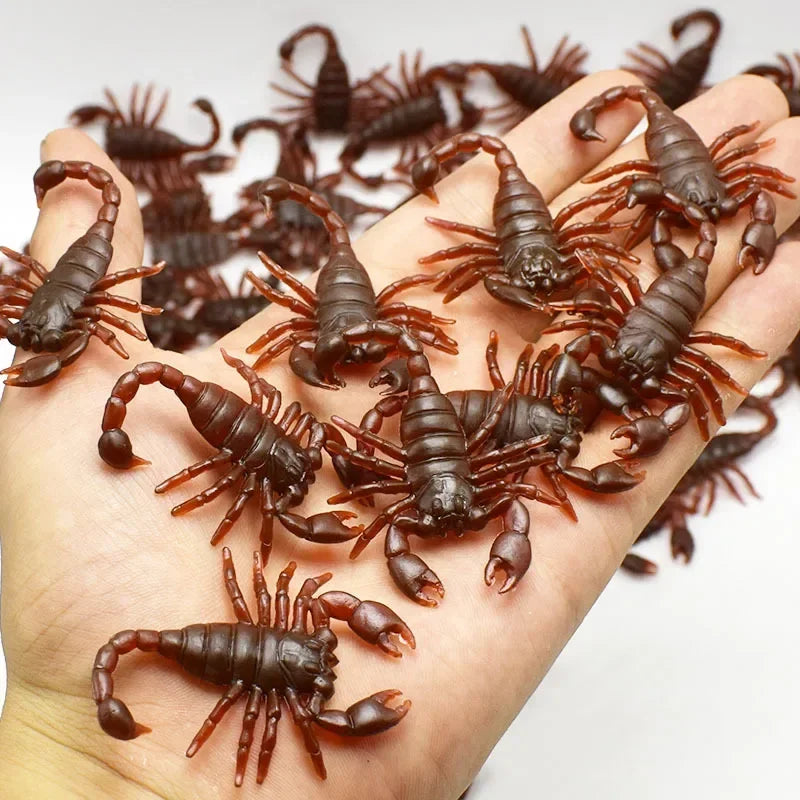 A hand holds a collection of realistic plastic bugs including cockroaches, centipedes, and scorpions.
