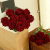 A bouquet of deep red velvet artificial roses in a brown paper bag.