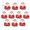 Un juego de nueve imanes navideños rojos con caras sonrientes de Santa y el texto 'Feliz Navidad'.