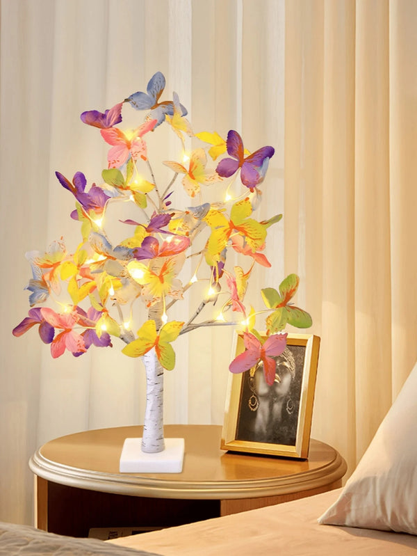 A decorative lamp shaped like a butterfly flower tree with warm glowing lights on a wooden table.