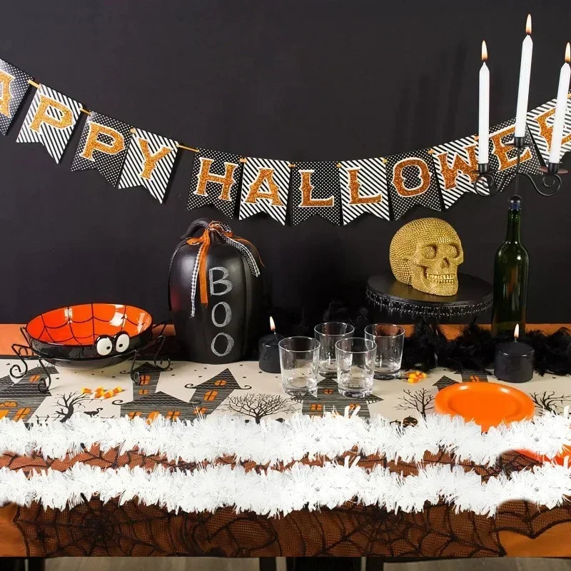 A Halloween decor display featuring a black pumpkin, a golden skull, and a banner strung with black and orange pennants.