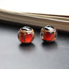 Pair of handcrafted lampwork glass beads with gold accents resting on a dark surface.