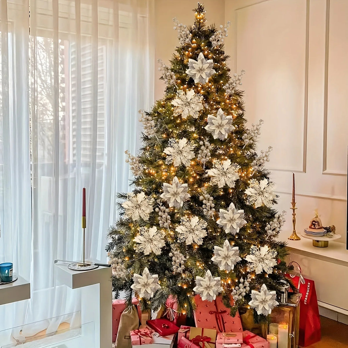 A decorated Christmas tree adorned with white flowers and lights in a bright room.