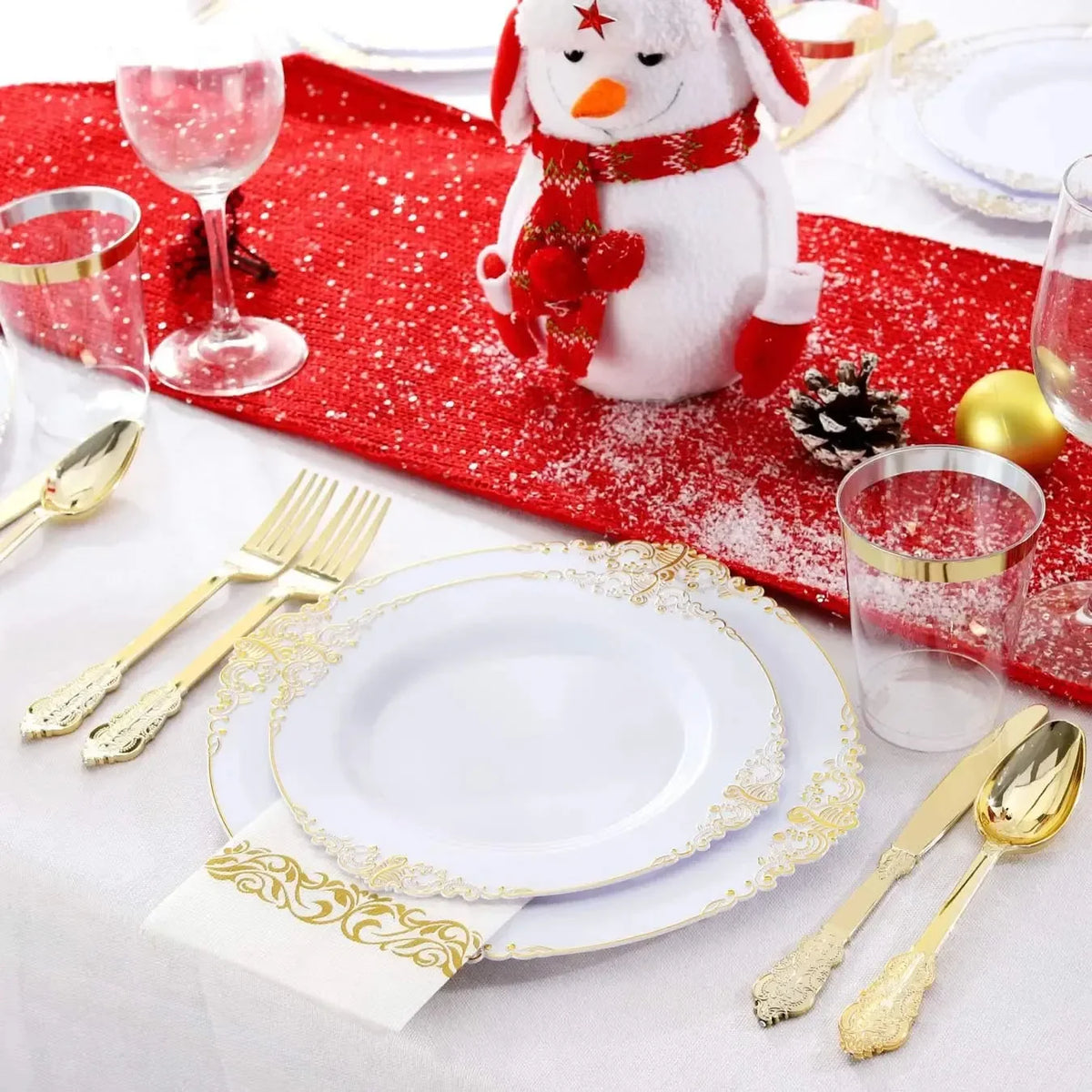 Elegant white and gold disposable dinnerware set with cutlery placed on a red festive cloth.