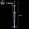 A set of seven clear, thin sticks arranged vertically on a circular base for balloon display.
