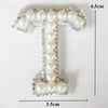 A rhinestone patch shaped like the letter T, featuring white pearls and blue crystals.