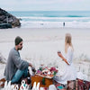 A couple sits on a beach with wooden letters spelling Mr and Mrs in the sand.