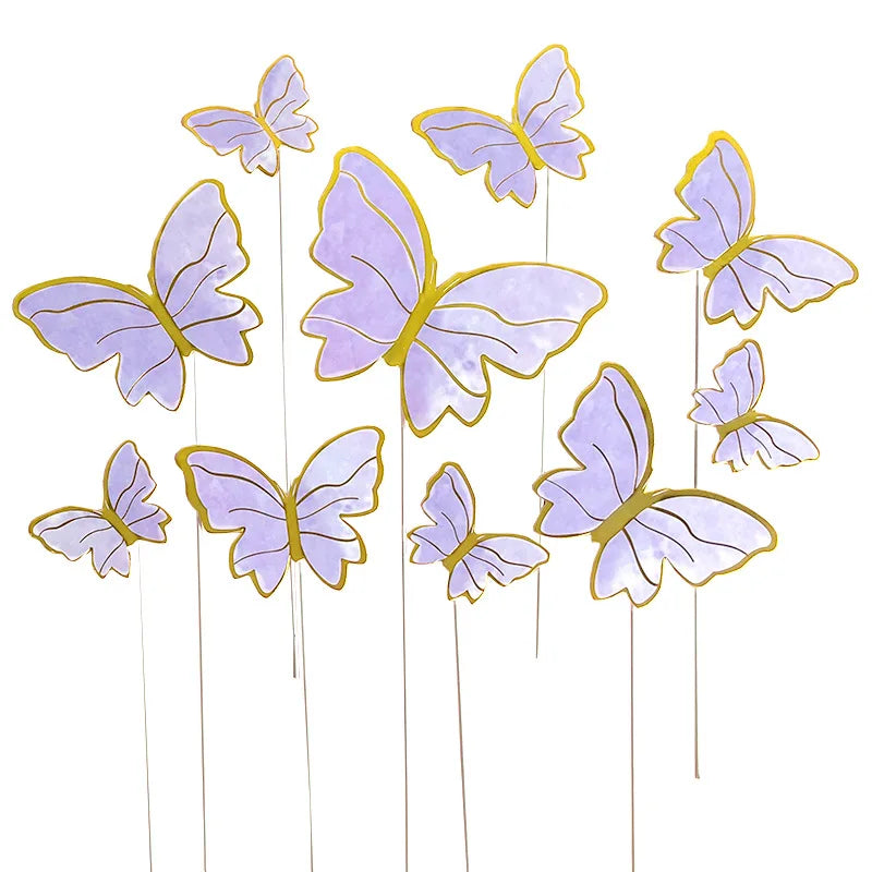 A collection of purple and gold paper butterfly cake toppers on thin sticks.