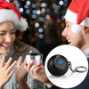 A close-up of a hand holding a black Magic 8 Ball keychain with a silver chain against a blurred background.