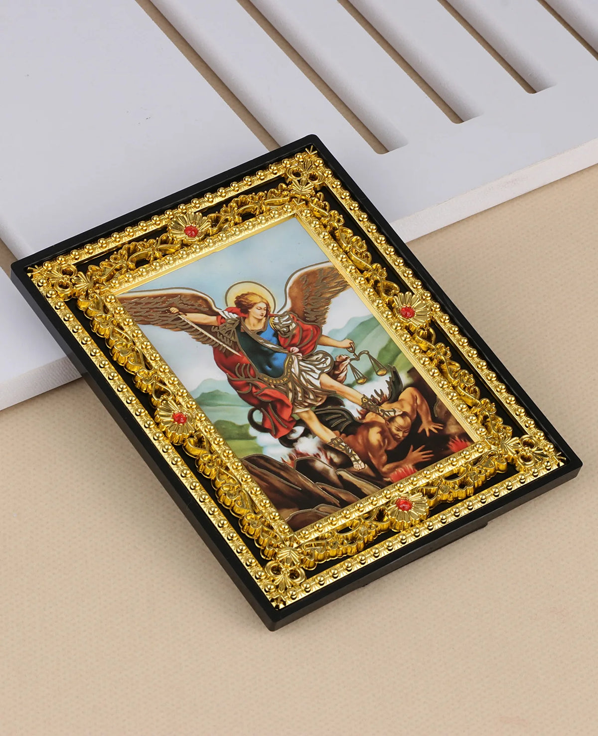 A framed Catholic icon depicting the Holy Family and Archangel St. Michael in gold and black ornate frame
