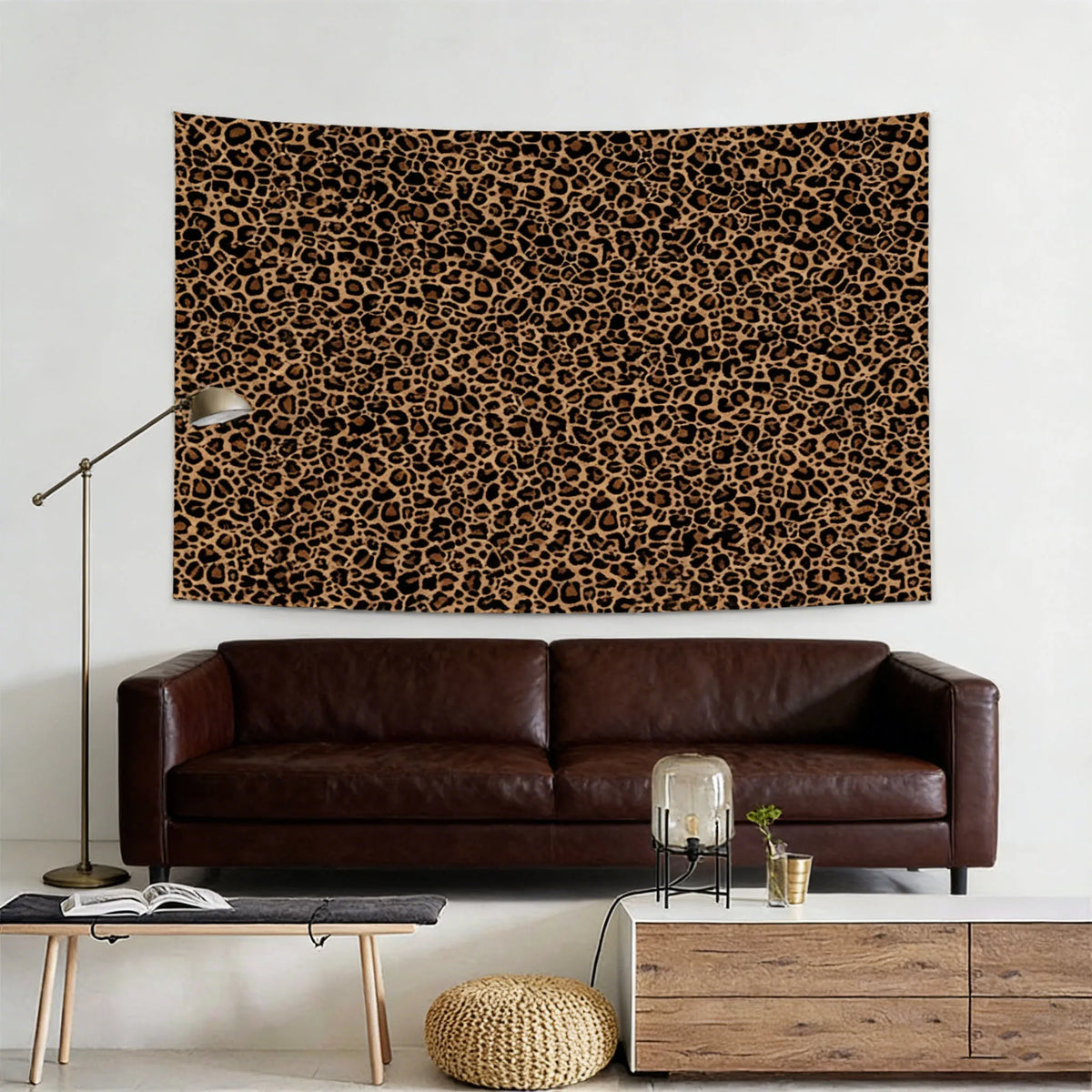 A dark brown leopard print tapestry wall hanging displayed above a dark leather sofa and modern furniture.