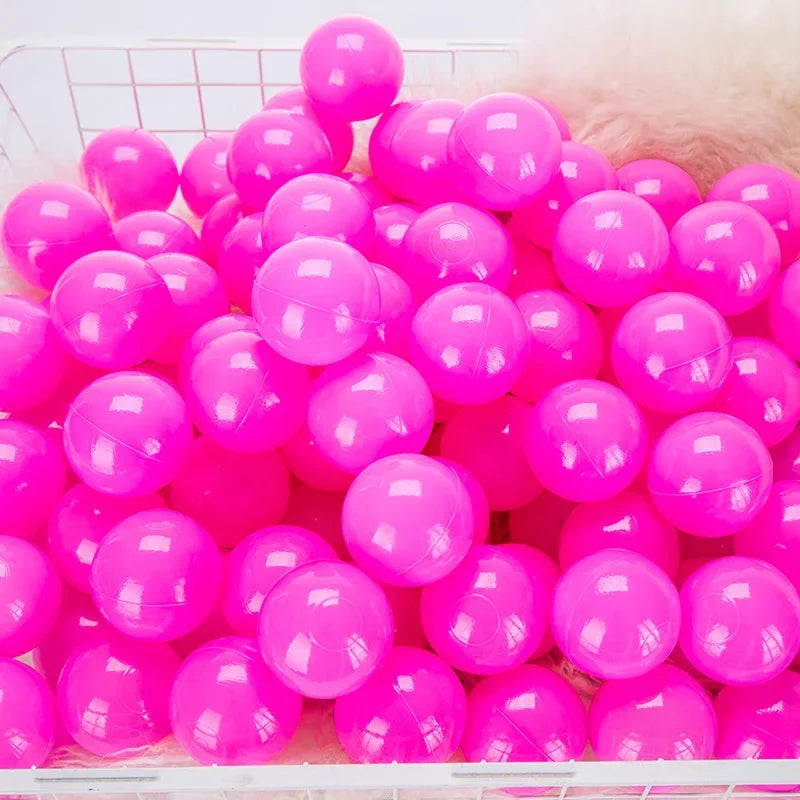 A large quantity of bright pink and purple plastic balls are displayed in a white crate.