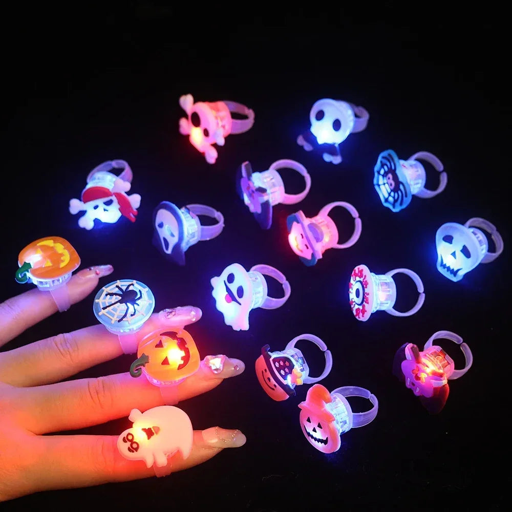 A hand holds several glow-in-the-dark Halloween rings with flashing lights against a dark background.
