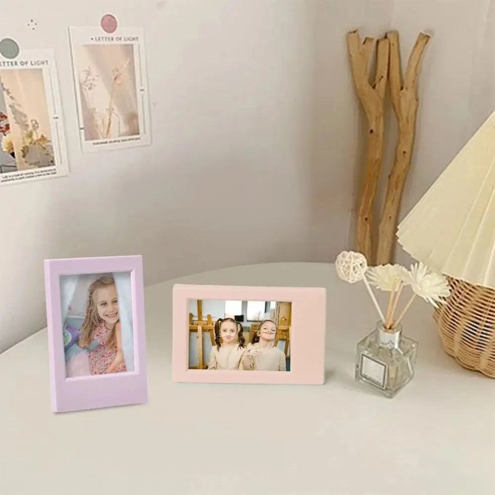 A pink mini film frame displaying two photos of young girls on a white surface.