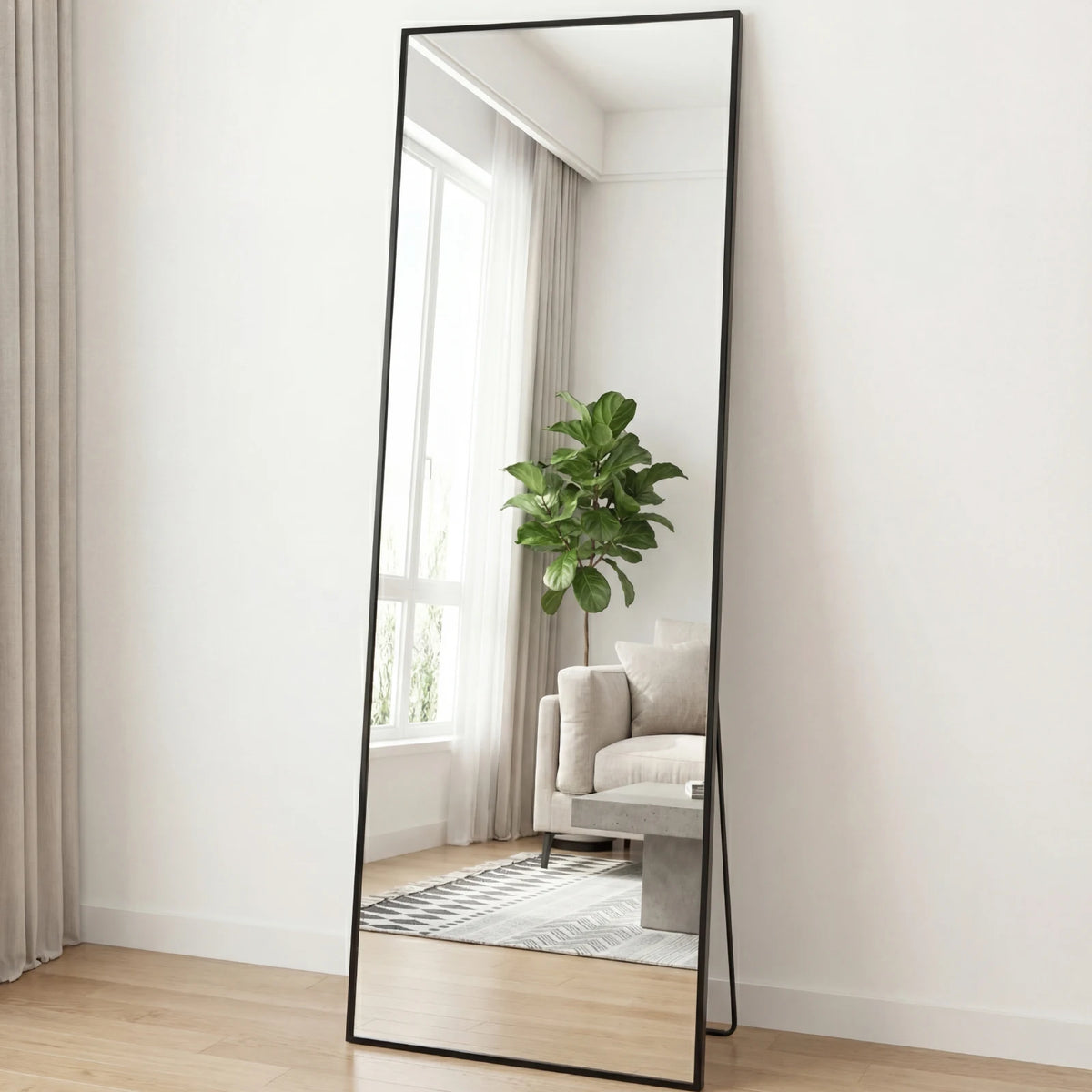 A full-length arched floor mirror with a black aluminum frame reflecting a window and indoor plants.