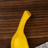 A bright yellow resin banana wall sculpture resting on a dark wooden surface.