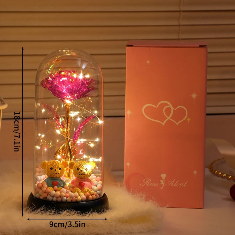 A glass dome containing an eternal rose light display sits next to its pink and gold packaging.