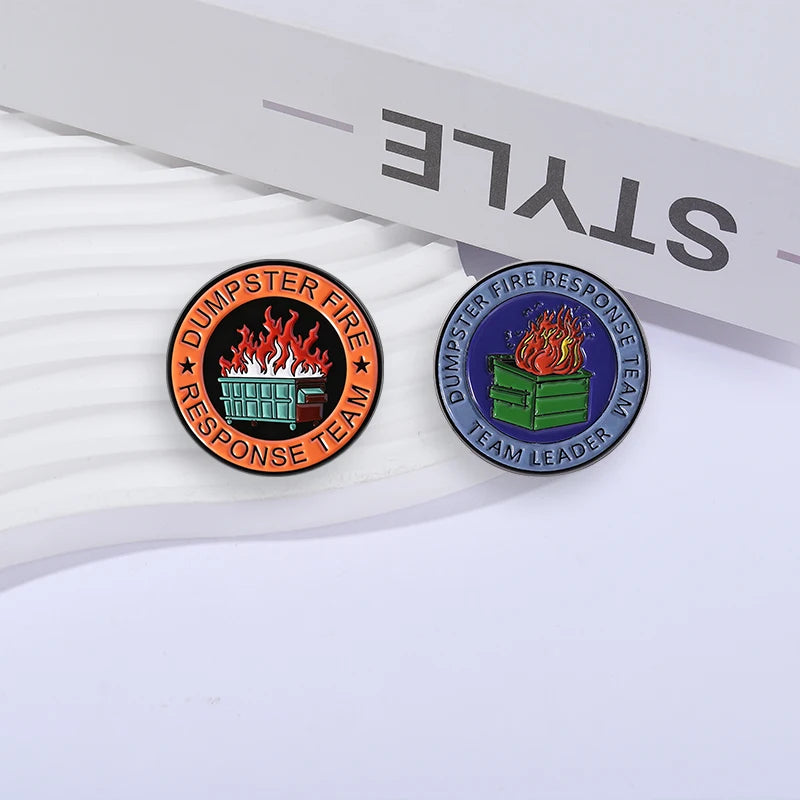 An enamel pin featuring a dumpster and flames, representing the Dumpster Fire Response Team Leader.
