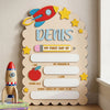 A wooden sign for a child named Denis featuring an airplane, stars, and text about his first day of school.