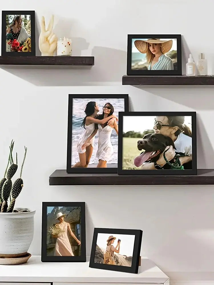 A set of five black wooden picture frames displaying various photographs and artwork for wall display.