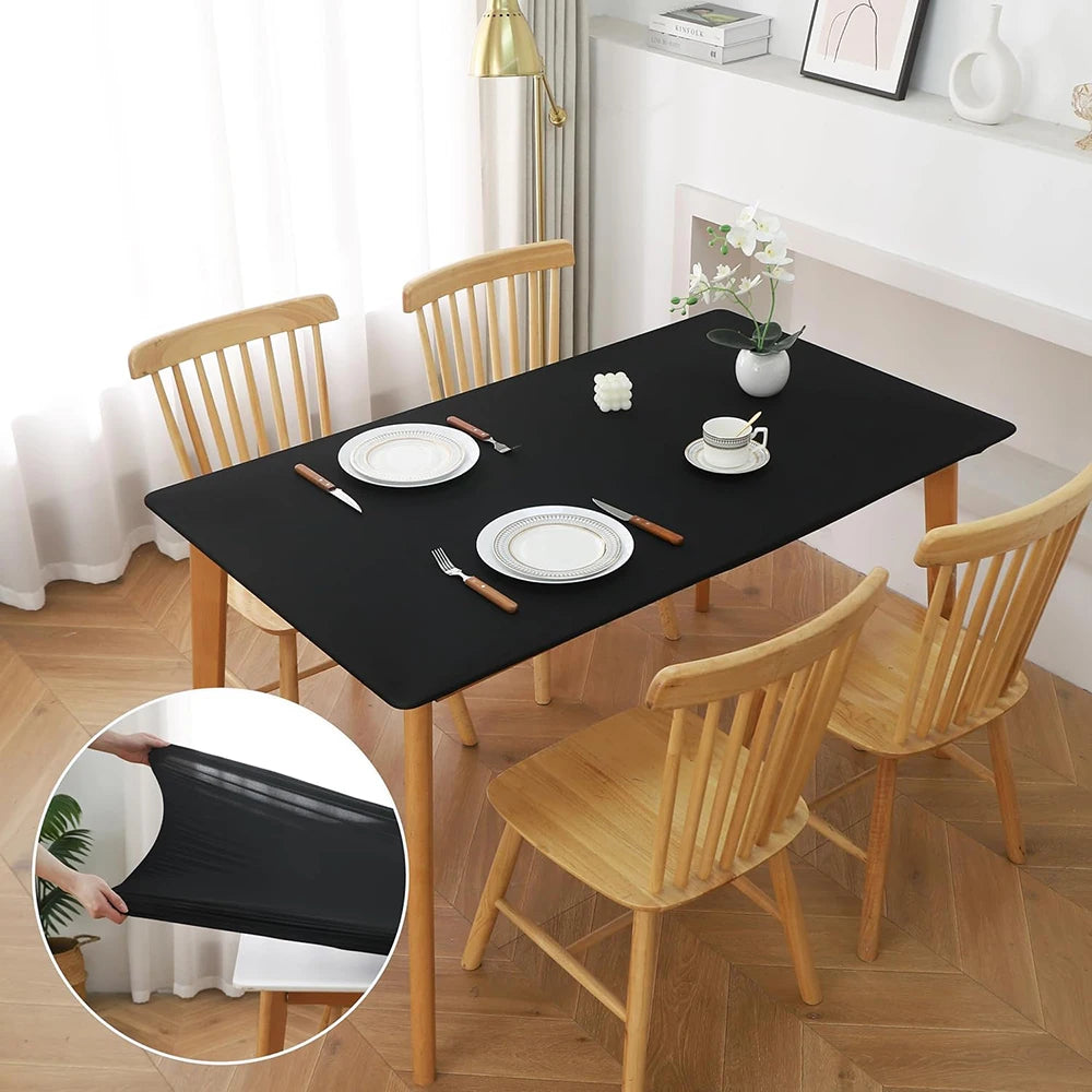 A black stretch tablecloth is draped over a wooden dining table in a bright room.