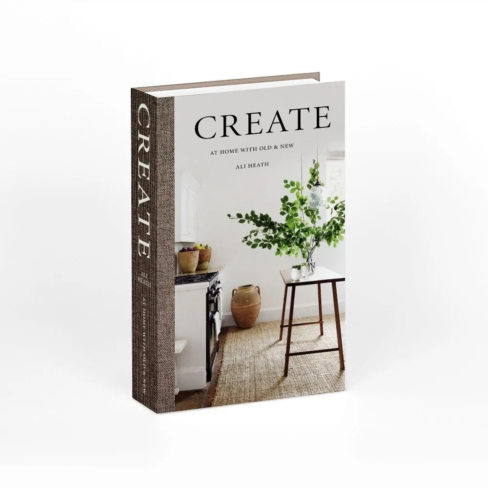 A hardcover book titled CREATE at home with old and new displayed on a wooden stand.