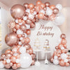 A large balloon garland featuring rose gold, pink, and white balloons arranged in an arch for a birthday celebration.