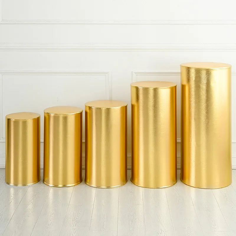 A row of tall, cylindrical gold spandex stands used for event decor.