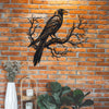 Black raven on a tree branch metal wall art displayed against an orange brick background.