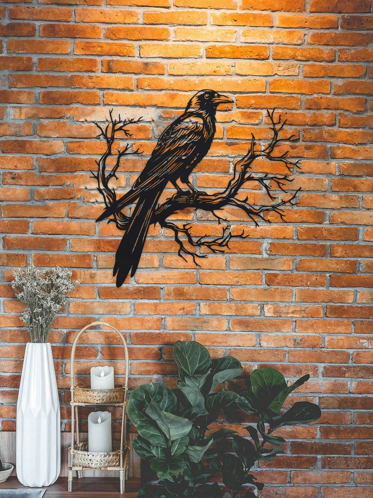 Black raven on a tree branch metal wall art displayed against an orange brick background.