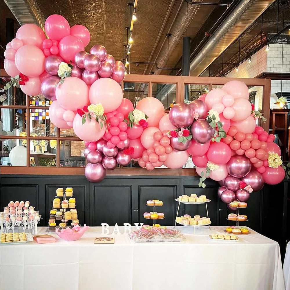 A display of pastel pink and white latex balloons with metallic confetti accents arranged on a table.