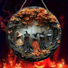 Circular wooden decor sign featuring witches and autumn leaves against a dark background.