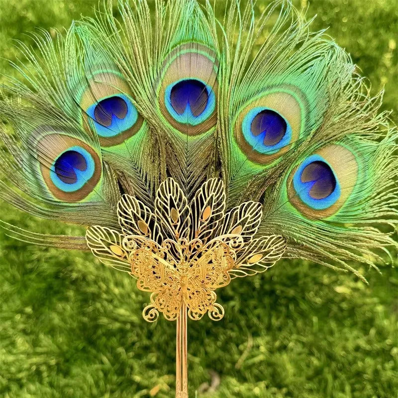 Plume de paon naturelle utilisée comme éventail, avec des plumes vertes et bleues vibrantes.
