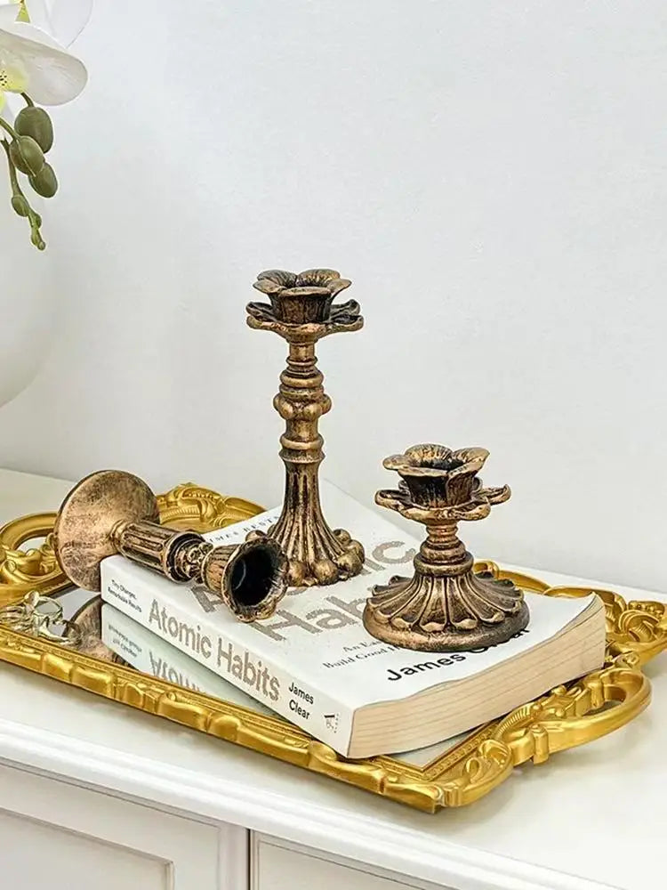 A vintage resin wall sconce candle holder displayed on a gold tray next to a book.