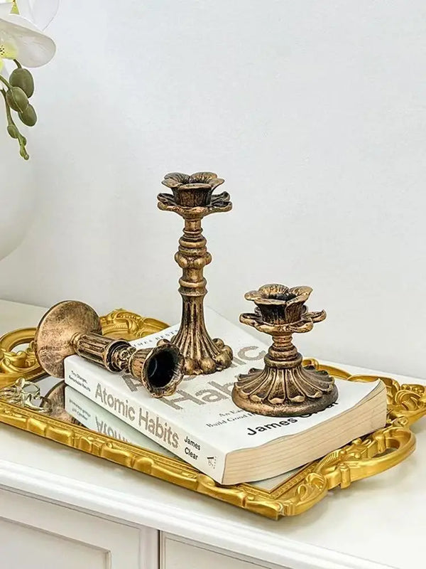 A vintage resin wall sconce candle holder displayed on a gold tray next to a book.