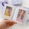 A hand holds an open clear plastic photo card album binder displaying a portrait of a male idol.