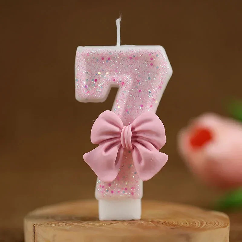 Vela número 7 rosa brillante con un lazo rosa sobre una superficie de madera.